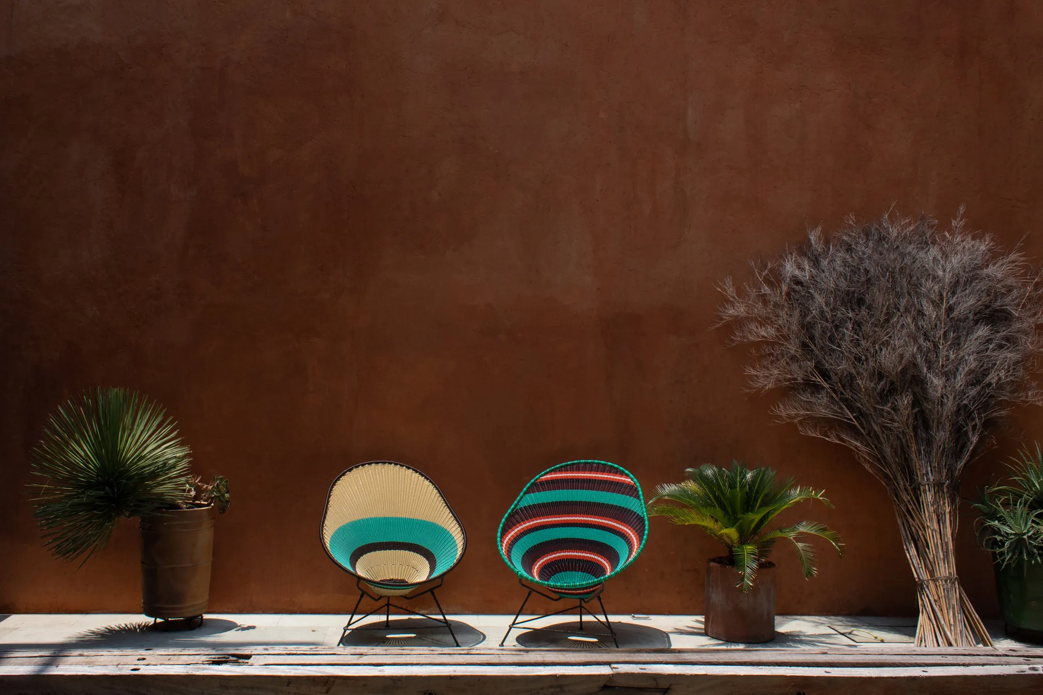 Sillas artesanales mexicanas de colores sobre un muro de barro