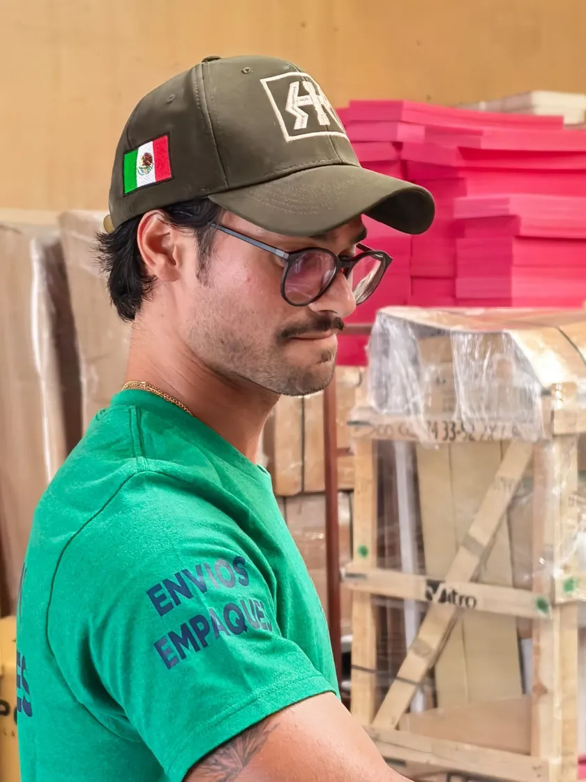 Trabajador de Sebastián Exportaciones junto a mobiliario embalado y protegido en el taller de Tlaquepaque